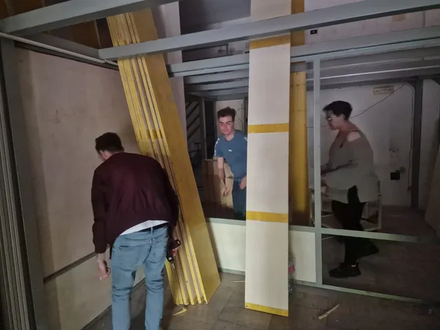 I fondatori trasportano assi di legno e avvitano i pannelli della nuova sede