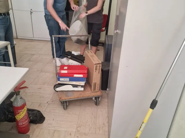 Il team riordina scatoloni e faldoni su un carrello durante l'allestimento degli uffici